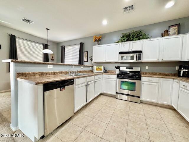 kitchen featuring white cabinetry, sink, kitchen peninsula, decorative light fixtures, and appliances with stainless steel finishes