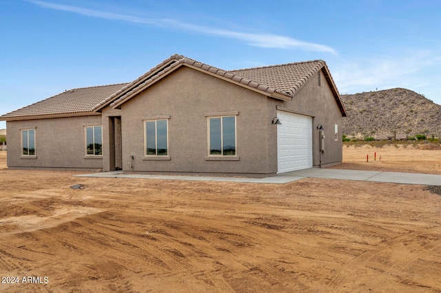 back of property with a mountain view and a garage