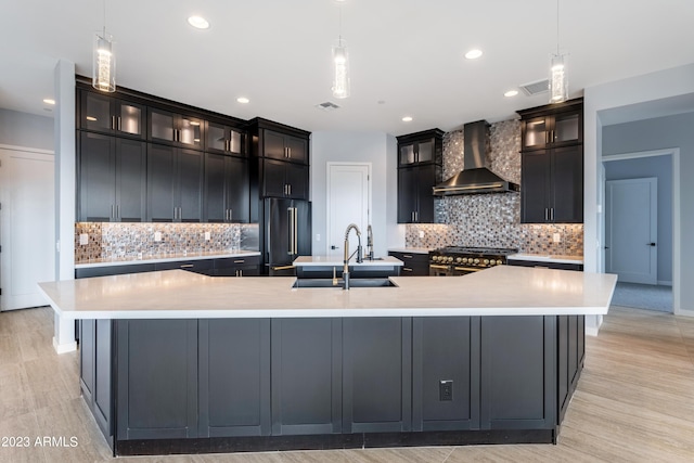 kitchen with a large island, sink, wall chimney exhaust hood, and appliances with stainless steel finishes