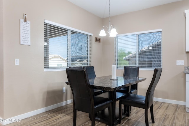 dining room with a wealth of natural light, wood tiled floor, a chandelier, and baseboards