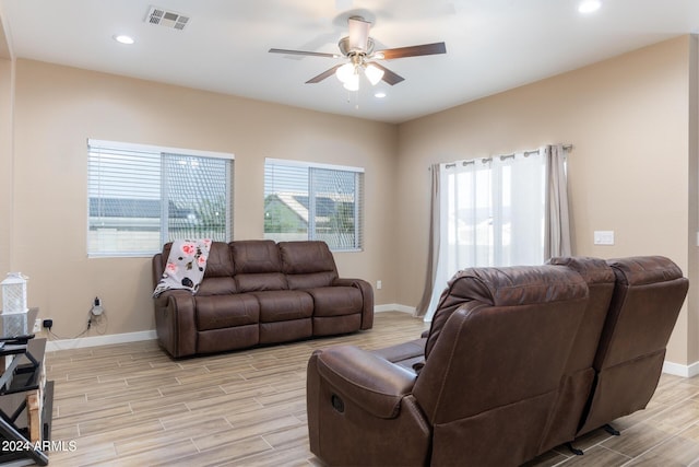 living room with ceiling fan, visible vents, baseboards, and wood finish floors