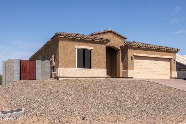 view of front of home featuring decorative driveway, a tiled roof, an attached garage, and stucco siding