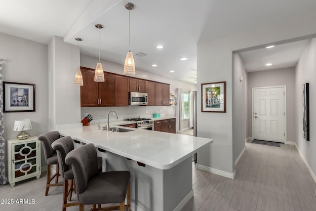 2597 E Hickory St, Gilbert, AZ 85298 - kitchen featuring stainless steel appliances, light countertops, a sink, a peninsula, and a kitchen bar