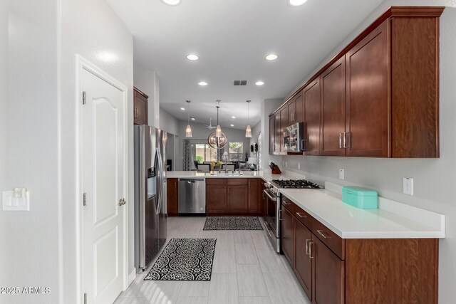 2597 E Hickory St, Gilbert, AZ 85298 - kitchen with stainless steel appliances, recessed lighting, light countertops, decorative light fixtures, and a peninsula