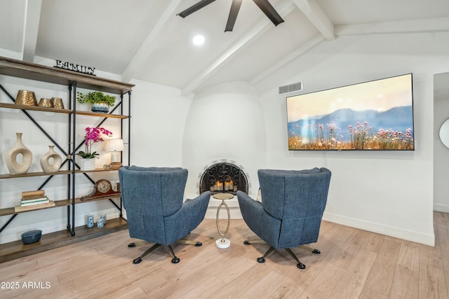 living area featuring hardwood / wood-style floors, lofted ceiling with beams, and a fireplace