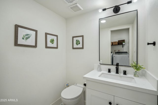 bathroom with toilet, vanity, and washer / dryer