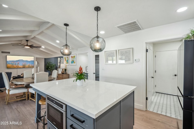 kitchen with pendant lighting, lofted ceiling with beams, gray cabinets, refrigerator, and light hardwood / wood-style floors