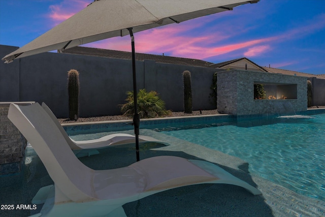 pool at dusk featuring a fenced backyard and a fenced in pool