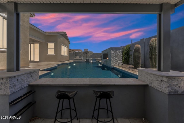 view of swimming pool featuring a patio, a fenced in pool, a fenced backyard, and outdoor dry bar
