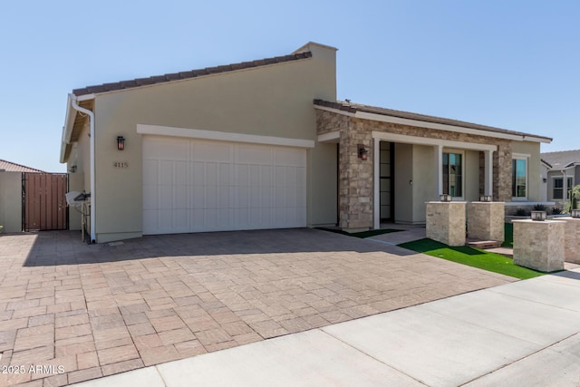 view of front of home featuring a gate, decorative driveway, an attached garage, and stucco siding