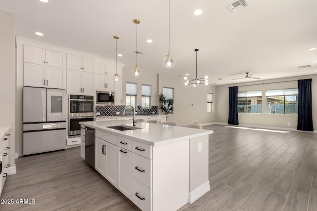 kitchen with open floor plan, light countertops, stainless steel appliances, a sink, and visible vents