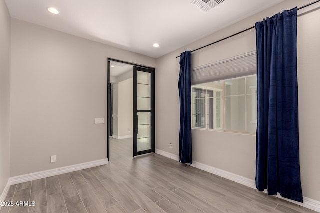 spare room with wood finished floors, recessed lighting, baseboards, and visible vents