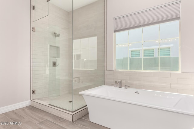 bathroom featuring a shower stall, baseboards, and a soaking tub