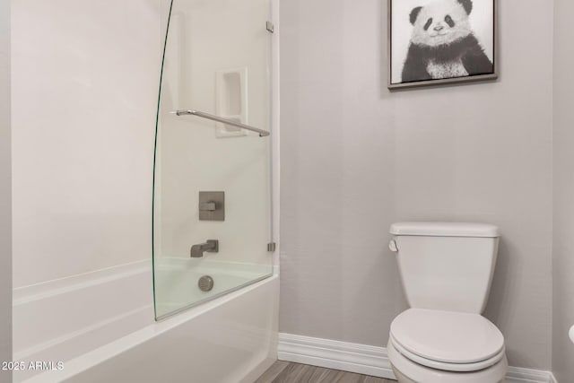 full bath with baseboards, wood finished floors, toilet, and shower / bathtub combination