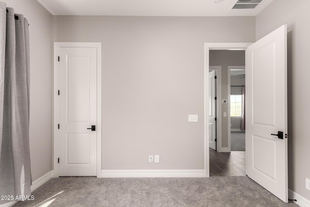 unfurnished bedroom with carpet floors, baseboards, and visible vents