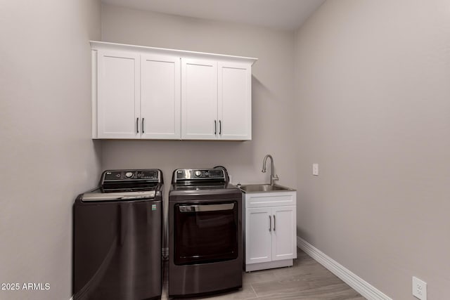 laundry area with a sink, cabinet space, washing machine and dryer, and baseboards