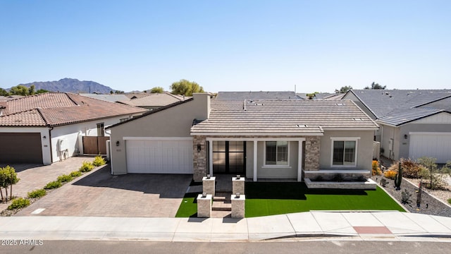view of front facade featuring a tile roof, driveway, stucco siding, and an attached garage