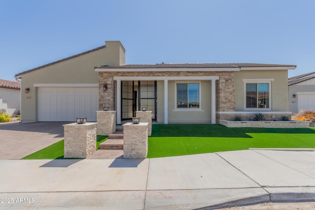 view of front facade featuring stone siding, a garage, stucco siding, a front yard, and driveway
