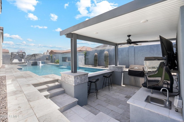 view of pool with a patio, outdoor wet bar, a fenced backyard, and a ceiling fan