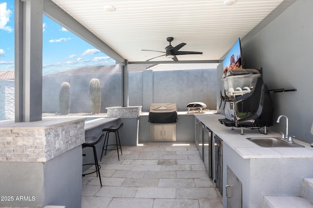 view of patio featuring outdoor wet bar, exterior kitchen, a sink, and a ceiling fan