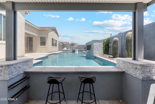 view of swimming pool featuring a patio, a fenced in pool, a fenced backyard, and outdoor dry bar