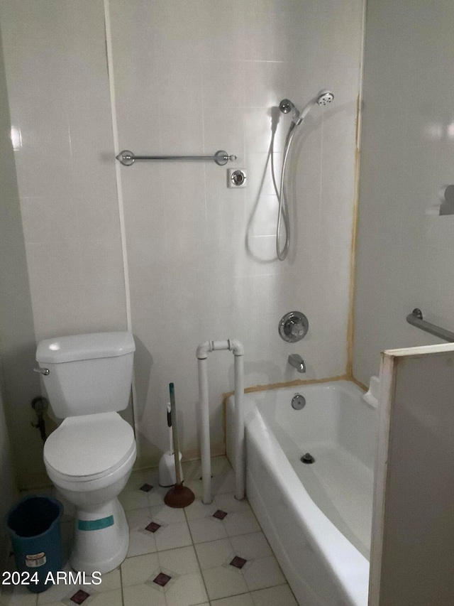 bathroom featuring toilet, tiled shower / bath combo, and tile patterned flooring