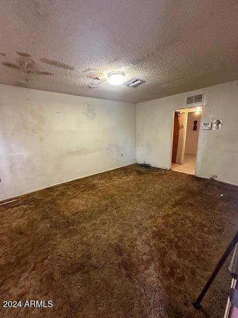 unfurnished room with a textured ceiling and light colored carpet