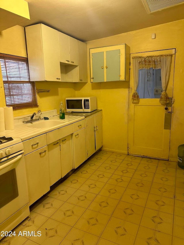 kitchen featuring white appliances, light tile patterned flooring, and sink