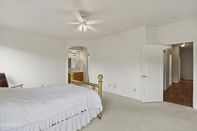 bedroom with arched walkways, ceiling fan, ensuite bath, and light colored carpet