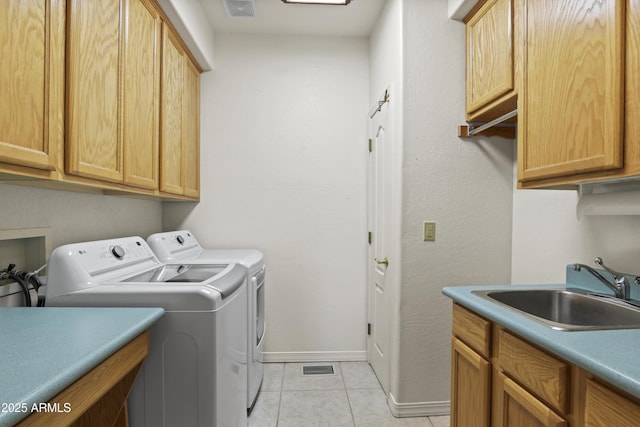 laundry room with light tile patterned floors, cabinet space, visible vents, washing machine and dryer, and a sink