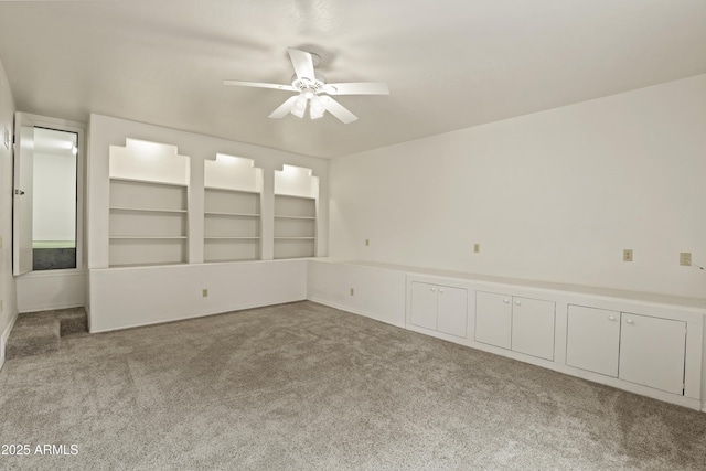 empty room featuring carpet, built in features, and ceiling fan