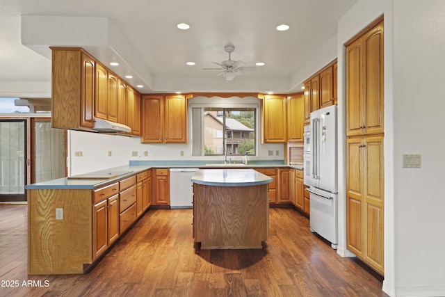 kitchen with dark wood-style floors, white appliances, a kitchen island, and recessed lighting