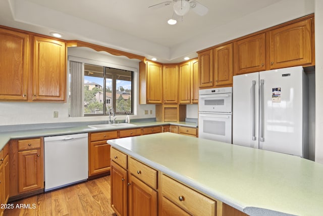 kitchen featuring light wood-style flooring, recessed lighting, white appliances, a sink, and light countertops