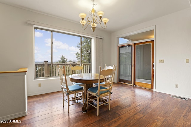 dining room with a chandelier, wood-type flooring, visible vents, and baseboards