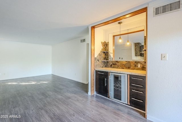 bar with hanging light fixtures, dark wood-type flooring, wine cooler, and decorative backsplash