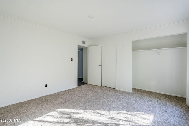 unfurnished bedroom featuring ornamental molding, two closets, and light colored carpet