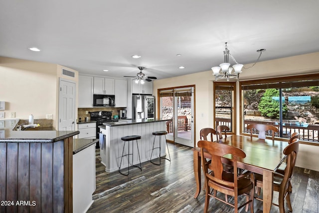 dining area with ceiling fan with notable chandelier, dark wood-type flooring, and plenty of natural light