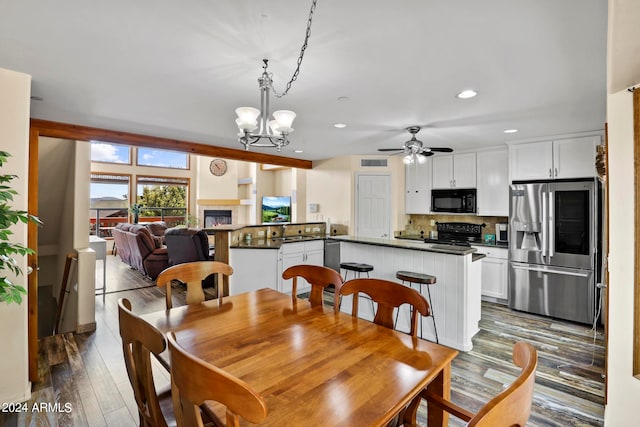 dining room with dark wood-type flooring and ceiling fan with notable chandelier