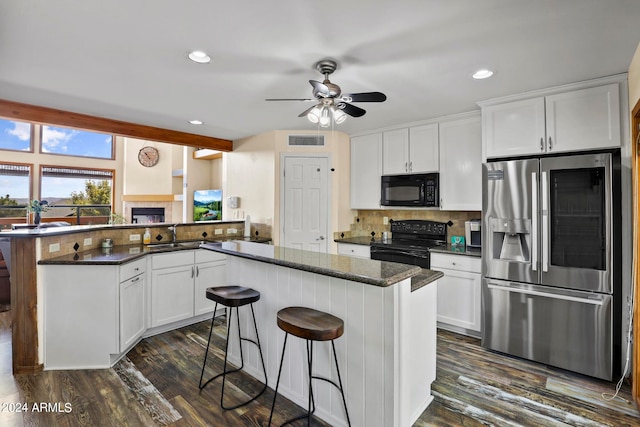 kitchen with decorative backsplash, black appliances, dark stone counters, a kitchen island, and ceiling fan