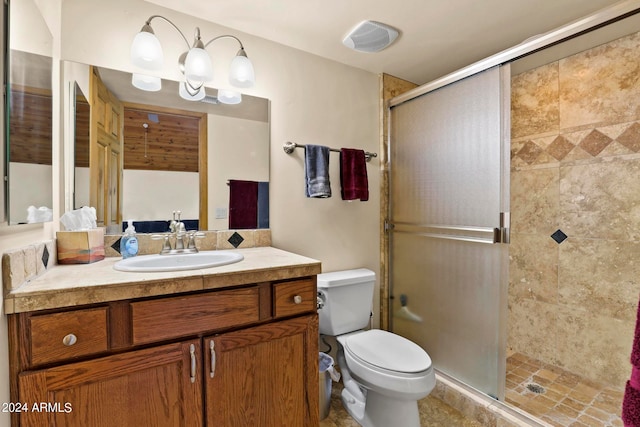 bathroom with a shower with shower door, toilet, vanity, and tile patterned floors