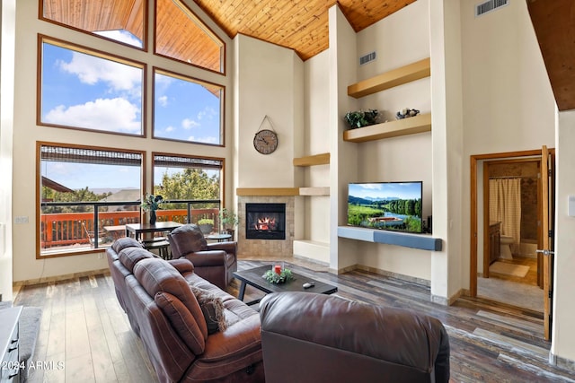 living room featuring high vaulted ceiling, wood ceiling, a tile fireplace, and built in features