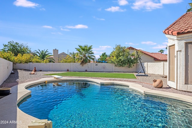 view of swimming pool with a diving board and a yard