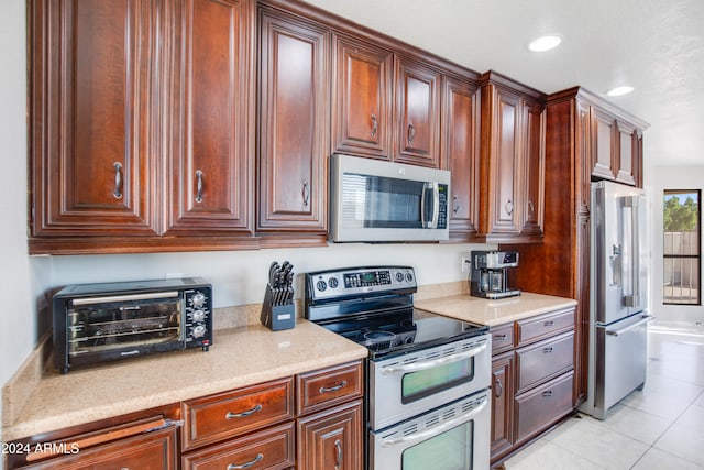 kitchen featuring light stone countertops, stainless steel appliances, and light tile patterned flooring