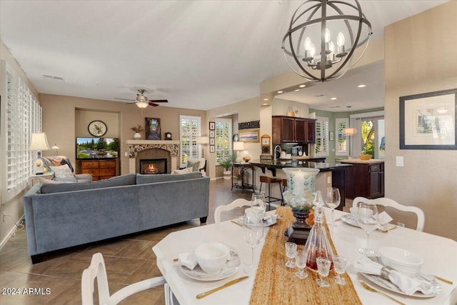 tiled dining room with ceiling fan with notable chandelier and sink