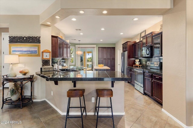 kitchen with a kitchen bar, backsplash, kitchen peninsula, and appliances with stainless steel finishes