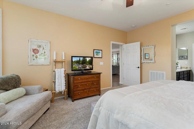 bedroom featuring light carpet, ensuite bathroom, and ceiling fan