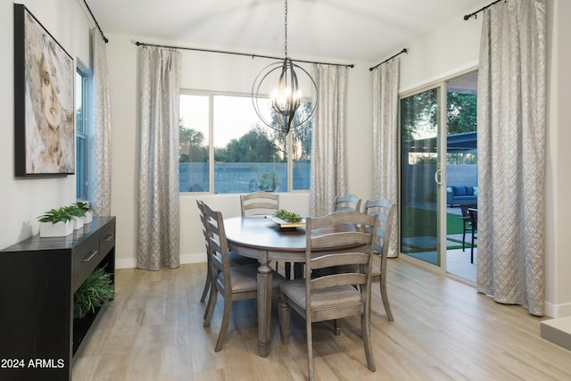 dining space featuring light wood finished floors, a chandelier, and baseboards