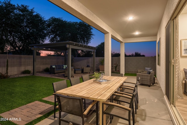 patio terrace at dusk featuring outdoor dining area, a fenced backyard, a lawn, and an outdoor hangout area