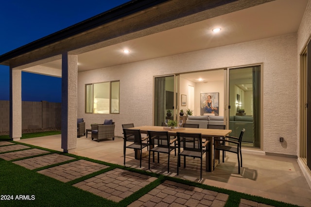 patio at twilight with outdoor dining area and fence