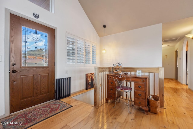 foyer with high vaulted ceiling and light wood-type flooring